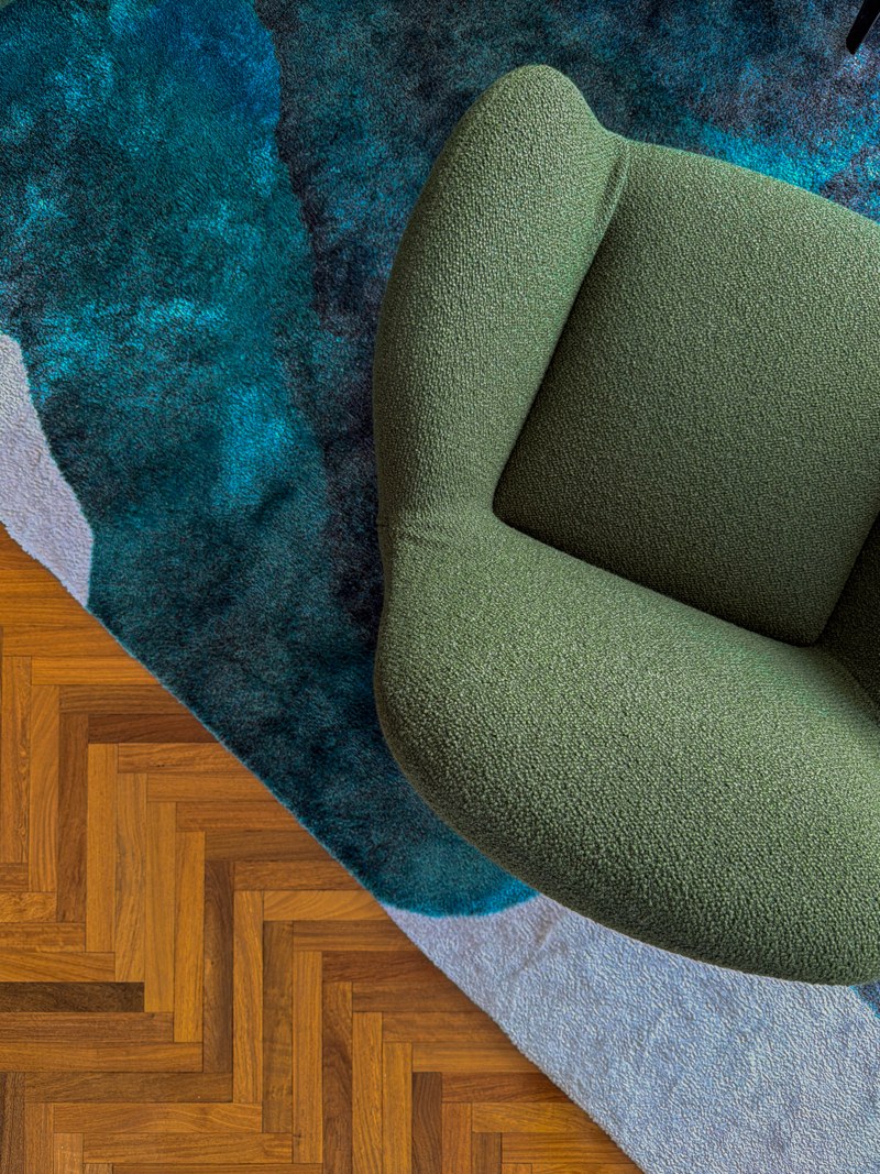 A sculptural chair and layered blue rug