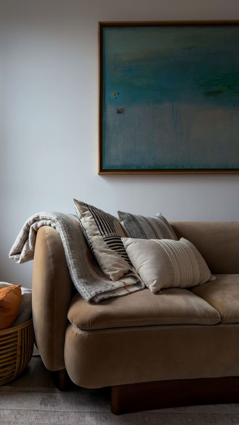Sofa and throw beneath a teal painting